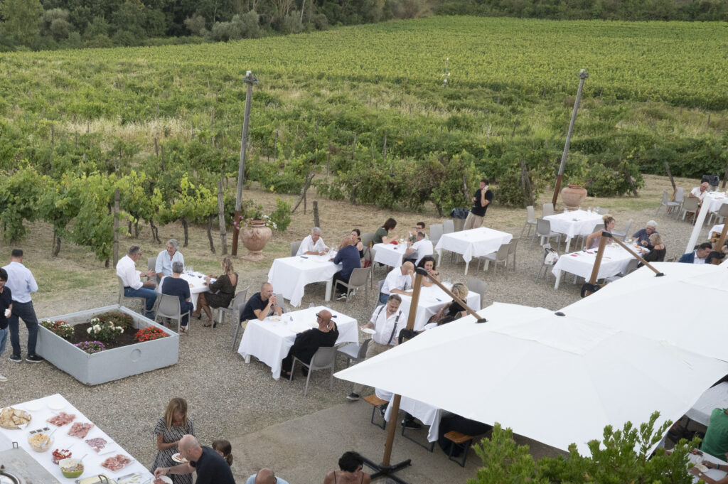 Wine tasting setup at Podere Ema with glasses of red and white wine overlooking the vineyards.