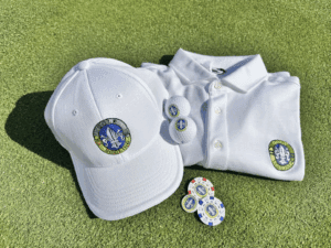 A white UC Golf cap, polo shirt, golf balls, and poker chips with the UC Golf logo arranged on a lush green surface, ideal for a golf outing.