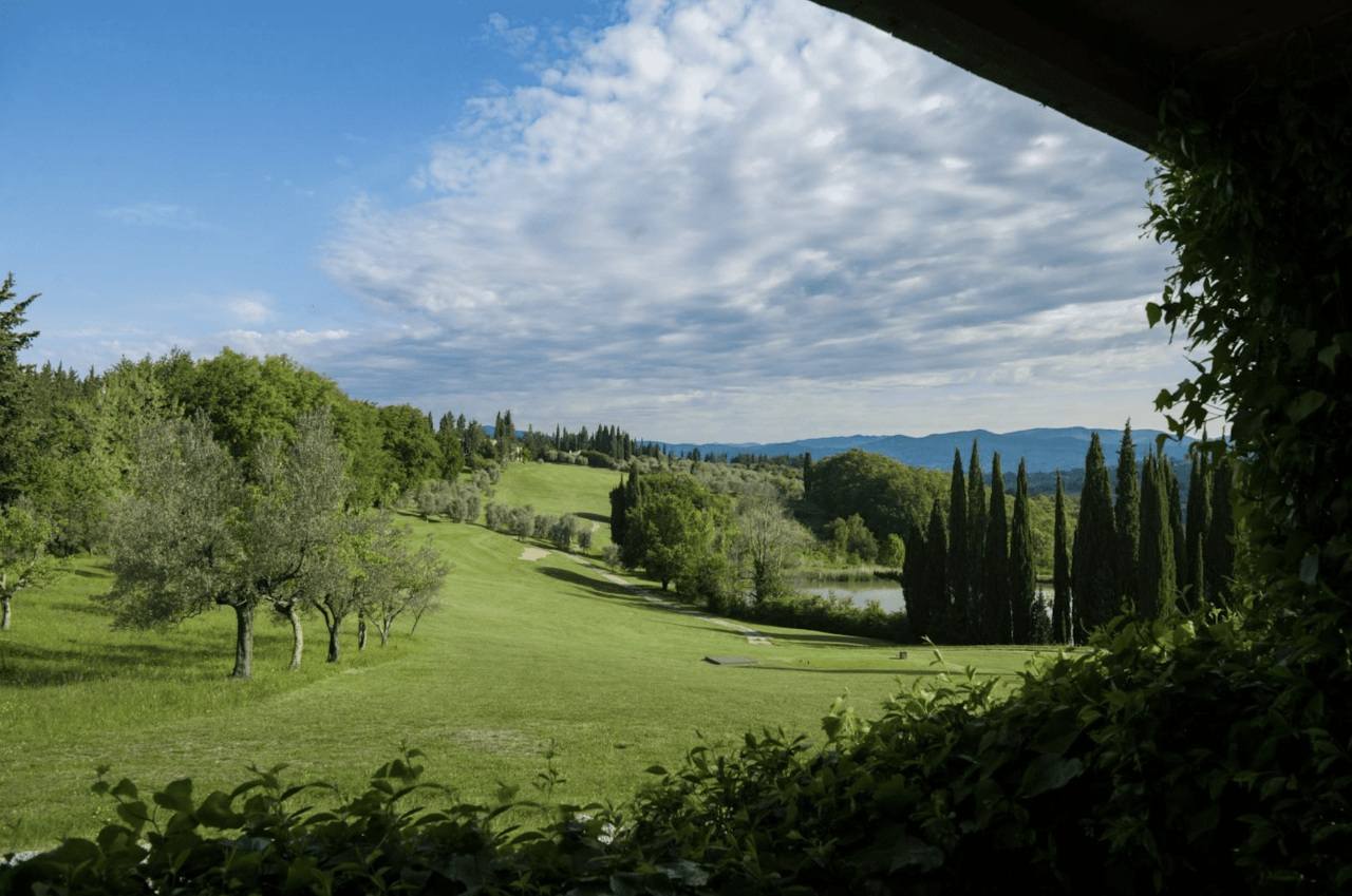 Scenic golf course in Tuscany with cypress and hills.