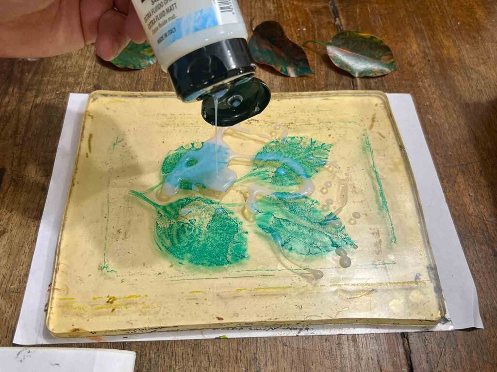 Pouring white medium over leaf impressions on the gel plate in a family art class Tuscany