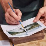 Hands carefully peeling a Polaroid emulsion from its white support during the Polaroid emulsion lift Florence session