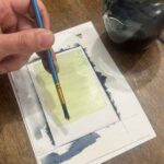 Applying light-sensitive emulsion to paper with a brush at a cyanotype class Florence, Fatacadabra
