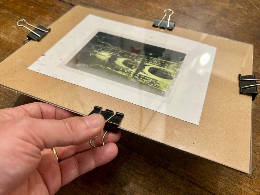 Securing negative and paper with binder clips before UV exposure at a cyanotype workshop Florence