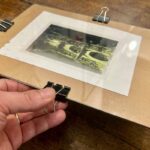 Securing negative and paper with binder clips before UV exposure at a cyanotype workshop Florence