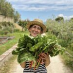 Local host holding a basket of fresh seasonal vegetables for a private Tuscan cooking class in Chianti.
