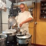 Chef stirring a pot at the stove during a private cooking class in Florence.