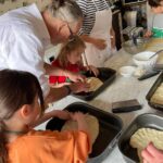 Children shaping dough with chef guidance during a family-friendly cooking class in Florence.