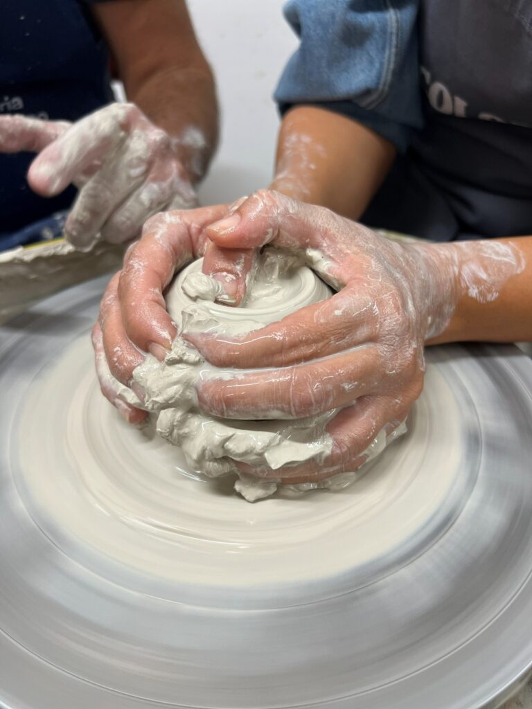 Guest shaping a ceramic vessel on the wheel during the hands-on workshop near Florence