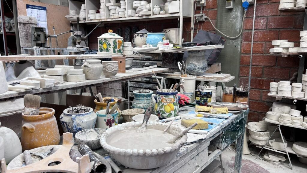 Pottery tools, brushes, and wet clay on a workshop table during a Tuscan ceramic masterclass.