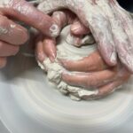 Close-up of guided technique during the pottery wheel class near Florence