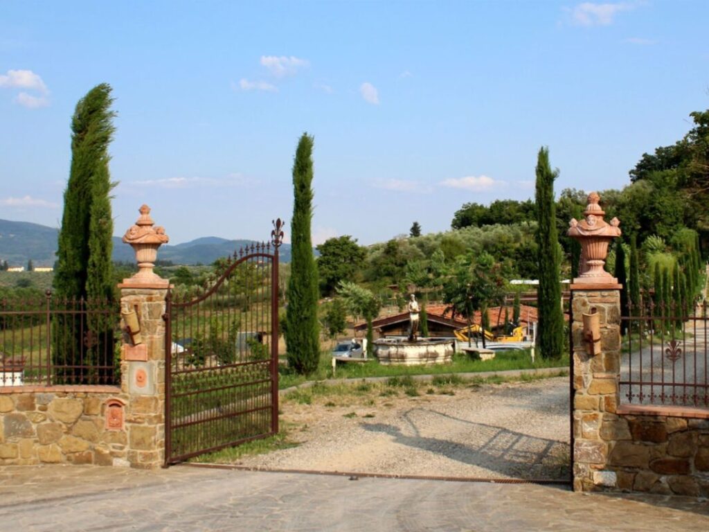 Iron gate entrance to Bio e Brado organic farm in Impruneta with cypress trees and Tuscan hills — farm animals Tuscany