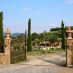 Iron gate entrance to Bio e Brado organic farm in Impruneta with cypress trees and Tuscan hills — farm animals Tuscany