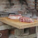 Local specialist preparing bistecca alla Fiorentina at a stone fireplace during a bistecca alla fiorentina experience at a Chianti winery near Florence.