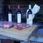 Thick cuts of bistecca alla Fiorentina and Chianti Classico bottles at Torci Brencoli winery, part of a bistecca alla fiorentina experience on a private wine tour tuscany.