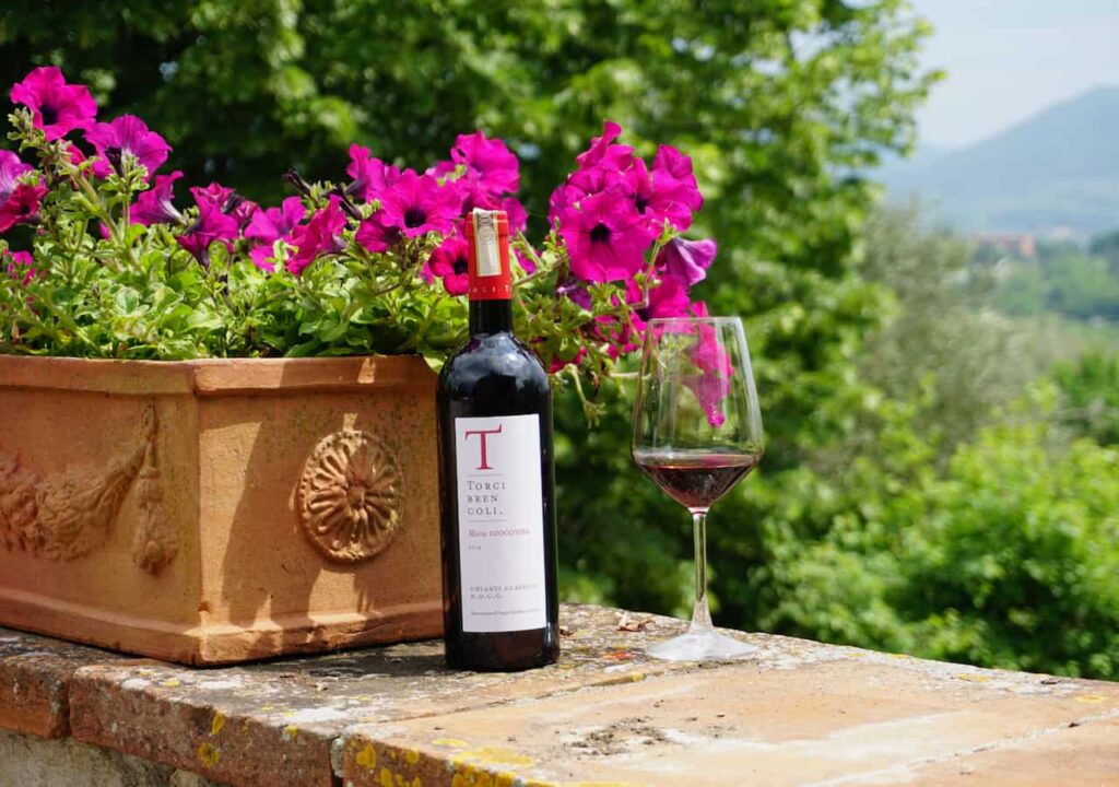 Bottle of Torci Brencoli Chianti Classico DOCG and a glass of red wine on a stone terrace, part of a private wine tour tuscany departing from Florence.