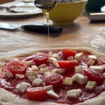 learn to make pizza in Florence adding toppings and olive oil