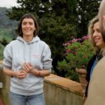 Local guide welcoming a small group on the terrace of a Chianti estate during a private wine tour tuscany, with rolling hills in the background.