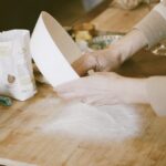 Hands pouring flour onto a wooden board to begin pasta dough on a family cooking class Tuscany.